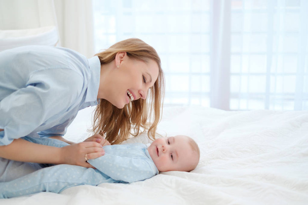 Happy middle aged mother with her child in a bed - Foto, Imagen