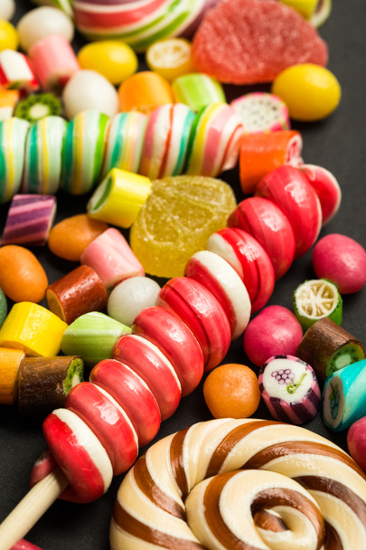 close up view of bright swirl lollipops among fruit caramel multicolored candies - Fotó, kép