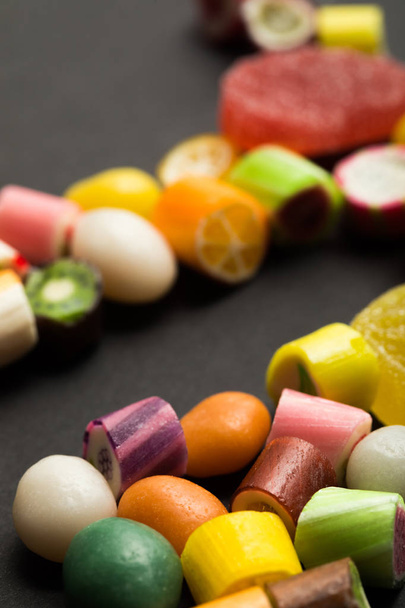 selective focus of delicious multicolored fruit caramel sweets on black background - Foto, Bild