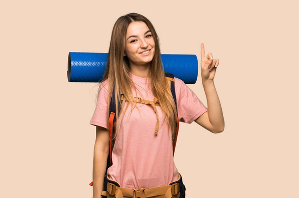 Young backpacker woman showing and lifting a finger in sign of the best on isolated yellow background - Fotografie, Obrázek