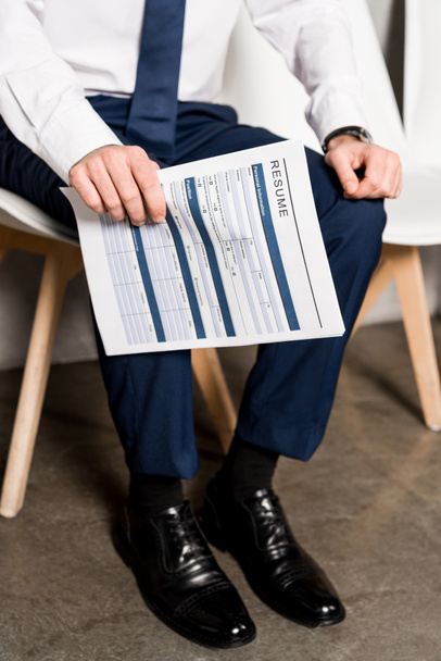 cropped view of man holding resume while sitting on chair  - 写真・画像