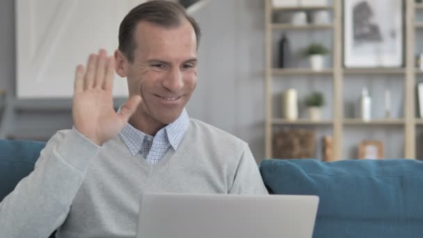 Chat de vídeo en línea en el ordenador portátil por el hombre de mediana edad sentado en el lugar de trabajo creativo
 - Imágenes, Vídeo
