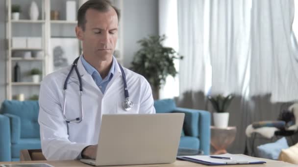 Senior Doctor Working On Laptop in Clinic - Filmagem, Vídeo