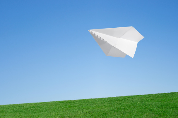 Mavi gökyüzü çim üzerinde uçan kağıt uçak - Fotoğraf, Görsel