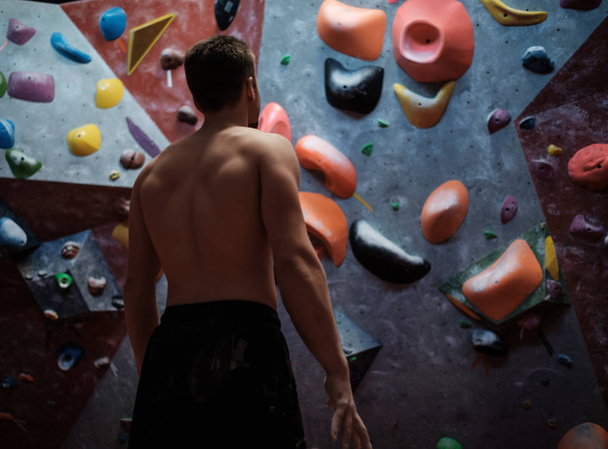 Athletic man stretching before climbing in a bouldering gym - Photo, Image
