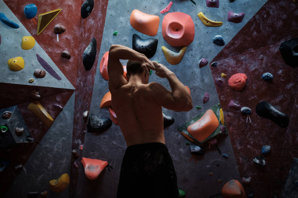 Hombre atlético estirándose antes de escalar en un gimnasio de bouldering
 - Foto, Imagen