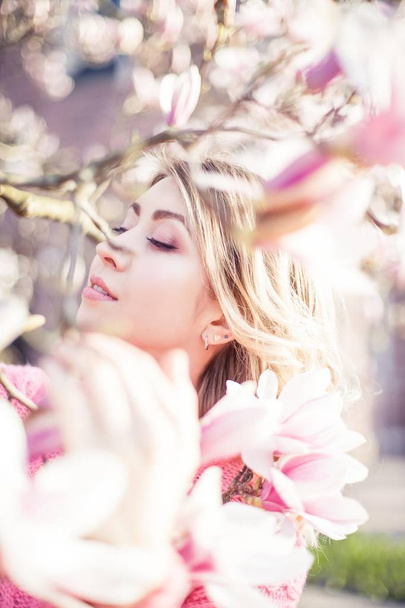 Portrait of a beautiful young woman near a magnolia. Spring. - Valokuva, kuva