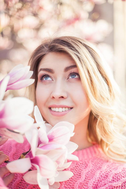 Portrait of a beautiful young woman near a magnolia. Spring. - 写真・画像
