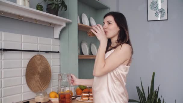 Young girl wearing pajamas drinking fresh juice in morning - Video, Çekim