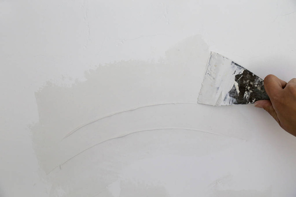 Parede de reboco com faca de vidraceiro, imagem de perto. Fixação da superfície da parede e preparação para a pintura
. - Foto, Imagem