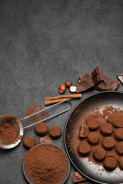 Chocolate truffles candies and cocoa powder on dark concrete background - Photo, image