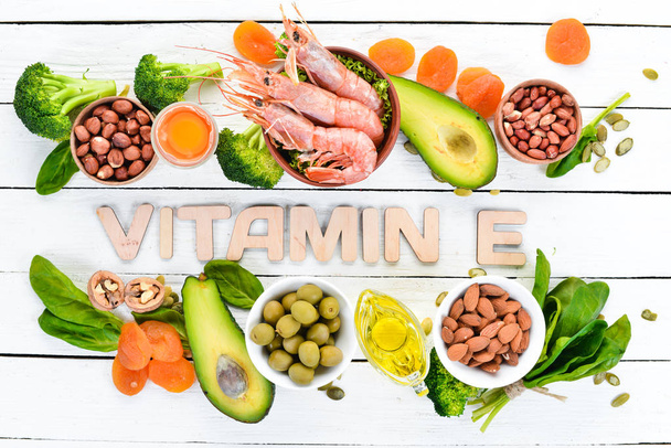 Food containing natural vitamin E: Spinach, parsley, shrimp, pumpkin seeds, eggs, avocados, broccoli. Top view. On a white wooden background. - Foto, immagini