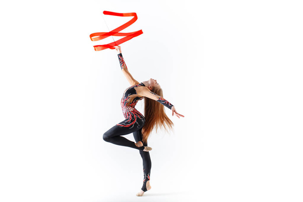 Gimnasia rítmica. Chica gimnasta joven con cinta roja sobre fondo blanco
 - Foto, Imagen