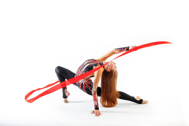 Rhythmic gymnastics. Young gymnast girl with red ribbon on white background - Photo, Image