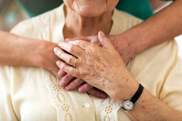 Verpleegster rooit haar oudere patiënt door haar handen te houden - Foto, afbeelding