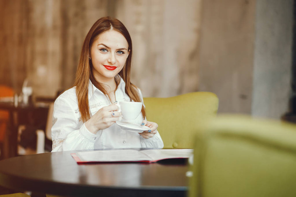 Beautiful girl sitting in a cafe - Fotó, kép