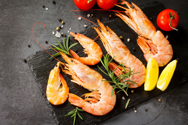 Seafood. Raw shrimps with spice, tomatoes and lemon on a slate b - Photo, Image