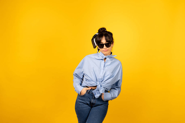 Young girl with in sunglasses posing for a photo on yellow background. - Foto, immagini