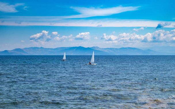 白い帆、青い空と海の背景を持つ小さな楽観主義のボート - 写真・画像