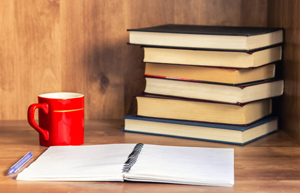 空白のノートブックと木製の背景コーヒー カップの閉じた本の山. - 写真・画像