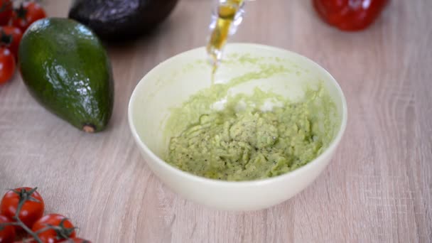 El cocinero vierte aceite de oliva en un tazón de guacamole. Concepto de comida saludable
. - Imágenes, Vídeo