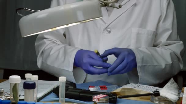 Scientific police examining and making photos of a bullet cap in ballistic Laboratory - Metraje, vídeo