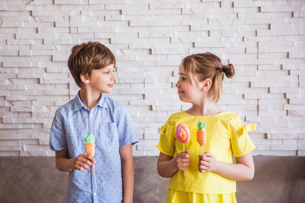 Imádnivaló lány és a fiú, aki színes édes habcsók egy bottal a húsvét napján - Fotó, kép