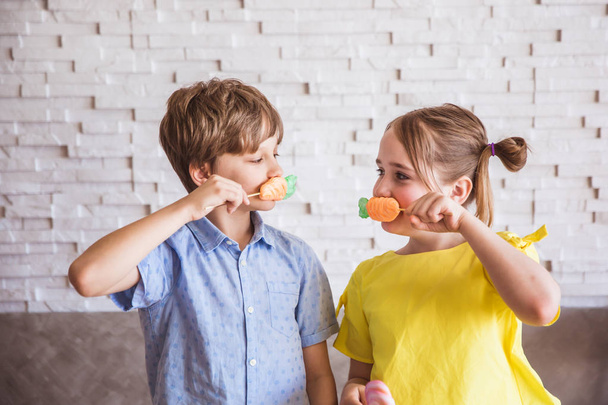 Adorable chica y niño sosteniendo coloridos merengues dulces en un palo en el día de Pascua
 - Foto, Imagen