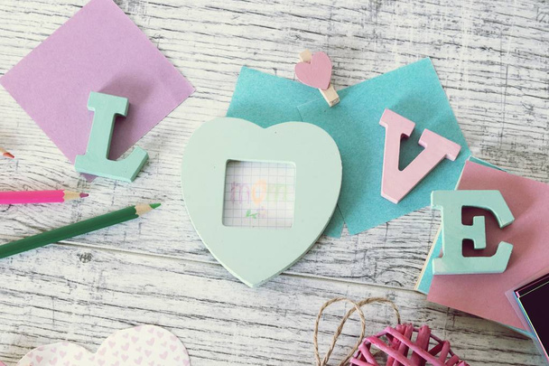 Mother's day holiday, composition of the word love from bulk letters, decor, paper, pencils on the table, top view - Photo, Image
