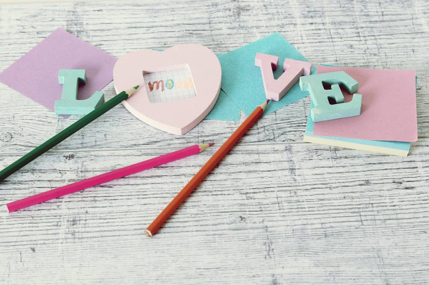Mother's day holiday, composition of the word love from bulk letters, decor, paper, pencils on the table, top view - Photo, Image