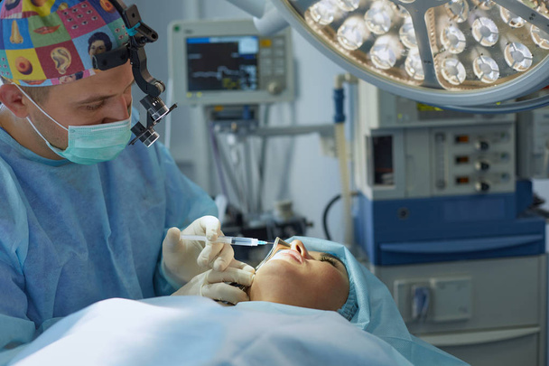 Vários médicos cercam o paciente na mesa de operação durante o trabalho. Cirurgiões de equipa a trabalhar na sala de operações
 - Foto, Imagem
