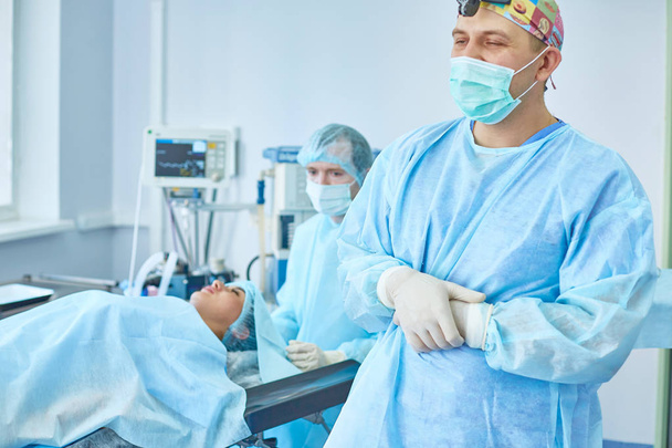 Mehrere Ärzte umgeben Patientin auf Operationstisch - Foto, Bild