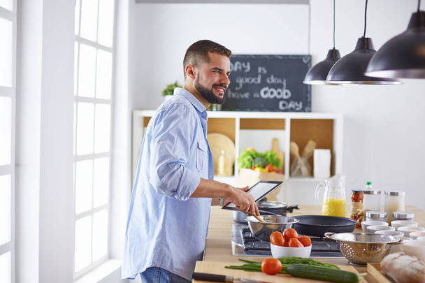 Glimlachende en zelfverzekerde chef-kok in grote keuken - Foto, afbeelding