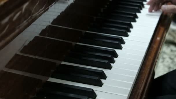 Adam piyano çalıyor. Genç bir adamın elleri bir müzik aletinin beyaz ve siyah tuşlarına basın. Genç bir piyanist bir konser prova. - Video, Çekim