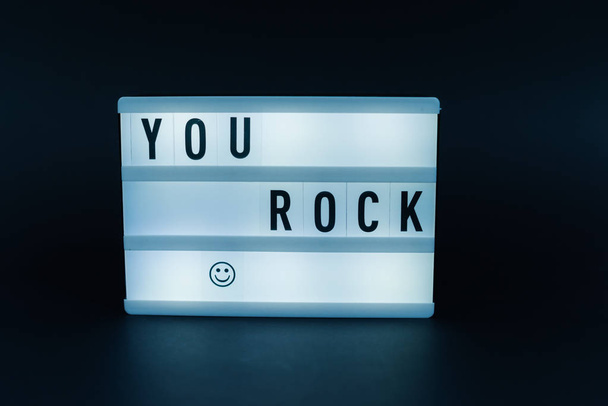 Photo of a light box with text, YOU ROCK, dark isolated background - Photo, Image