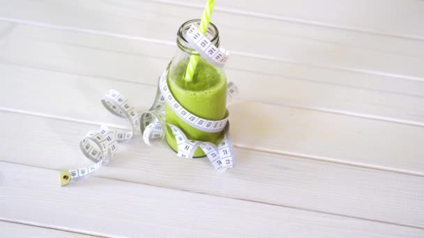 cóctel verde y vegano saludable con cinta de centímetro en la mesa de madera blanca
 - Metraje, vídeo
