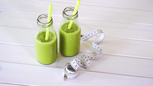 gezonde groene en veganistische cocktails met centimeter tape op witte houten tafel - Video