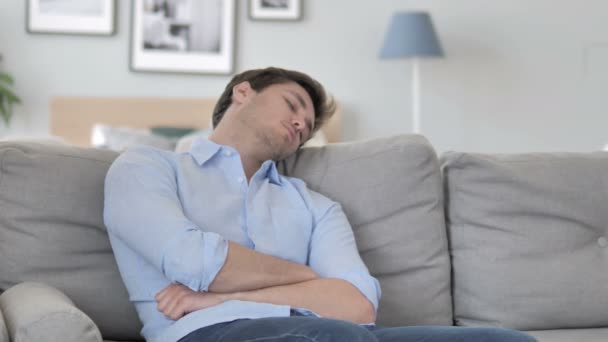 Κουρασμένος όμορφος νέος άντρας κοιμάται ενώ κάθεται στον καναπέ - Πλάνα, βίντεο