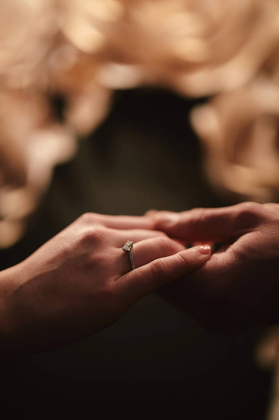 kezében egy fiatal házaspár a gyűrűt. szerelem, pár, kapcsolat és ünnepek koncepció-közelről az ember, amely gyémánt gyűrű nő - Fotó, kép