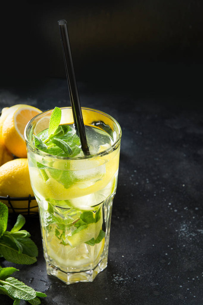 Mojito cocktail or lemonade with lime and mint in highball glass on black table. Close up. Summer drink. - 写真・画像
