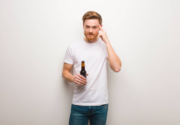 Young redhead man thinking about an idea. Holding a beer. - 写真・画像