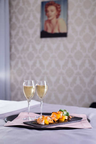Twee glazen champagne in de luxe hotelkamer. Dating, romantiek, huwelijksreis, uitje concepten. Licht warm toning - Foto, afbeelding