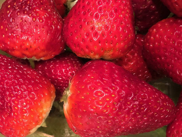 Gros plan de fraises assises ensemble dans une boîte attendant de manger. La fraise de jardin est une espèce hybride largement cultivée du genre Fragaria, collectivement connue sous le nom de fraises. Il est cultivé dans le monde entier pour ses fruits
.  - Photo, image