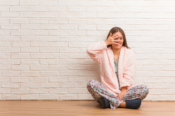 Jonge vrouw dragen pyjama beschaamd en lachen op hetzelfde moment - Foto, afbeelding