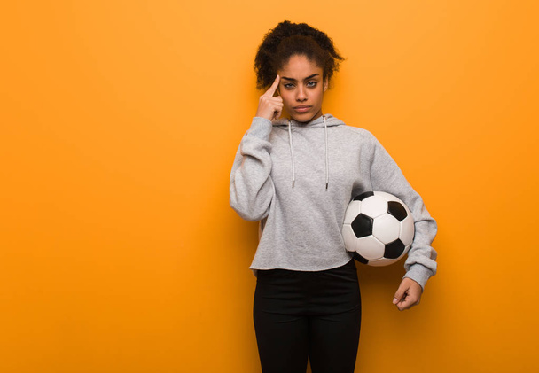 Młoda czarna kobieta robi gest koncentracji. Trzymanie piłki nożnej. - Zdjęcie, obraz