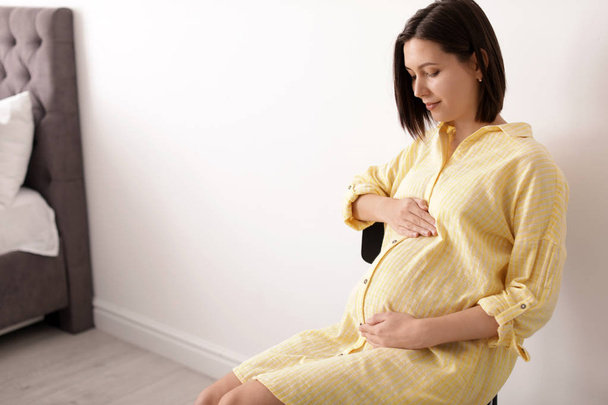 Gyönyörű terhes nő ül világos szobában. Szóköz a szöveghez - Fotó, kép