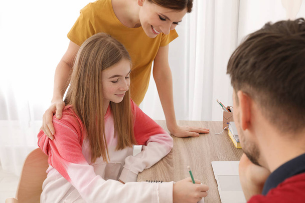 Parents helping their teenager daughter with homework indoors - Фото, изображение