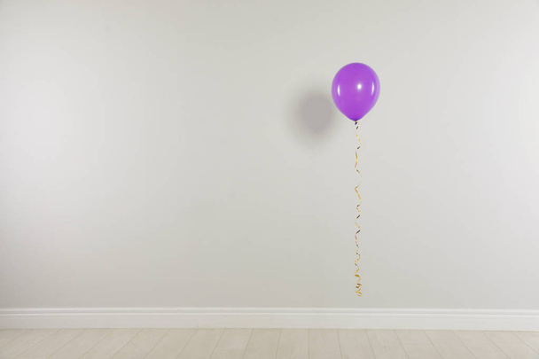 Bright balloon against light wall, space for text. Celebration time - Photo, Image