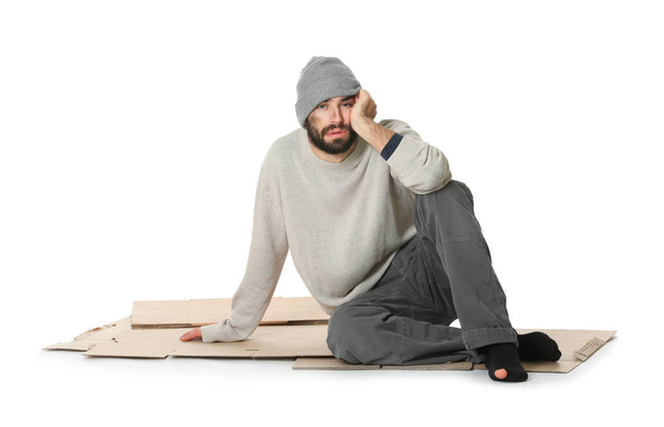 Poor homeless man sitting on cardboard, white background - Fotó, kép