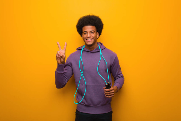 Fiatal afro-amerikai sportember kezében ugrókötél szórakoztató és boldog csinál egy gesztus a győzelem - Fotó, kép